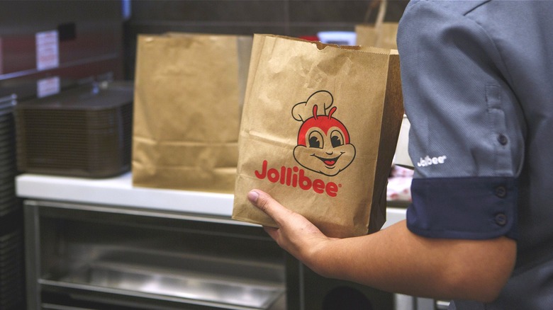 Employee holding Jollibee bag behind the counter