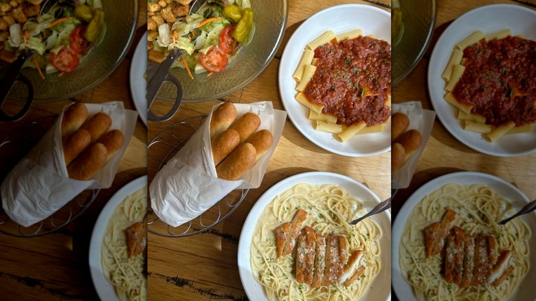 Olive Garden spread with pastas, breadsticks, and salad on table