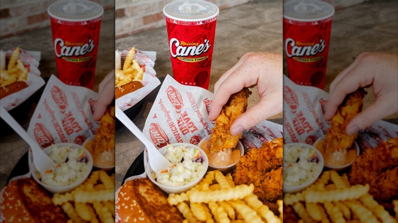 Someone dipping chicken in Cane's Sauce