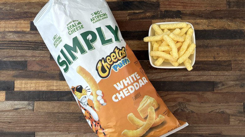 Simply Cheetos Puffs White Cheddar in bag and white bowl on wooden table