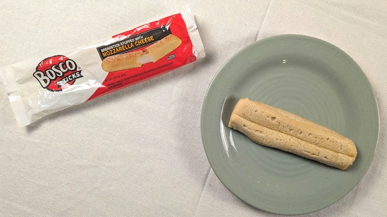 A mushy breadstick on a blue plate next to its wrapper