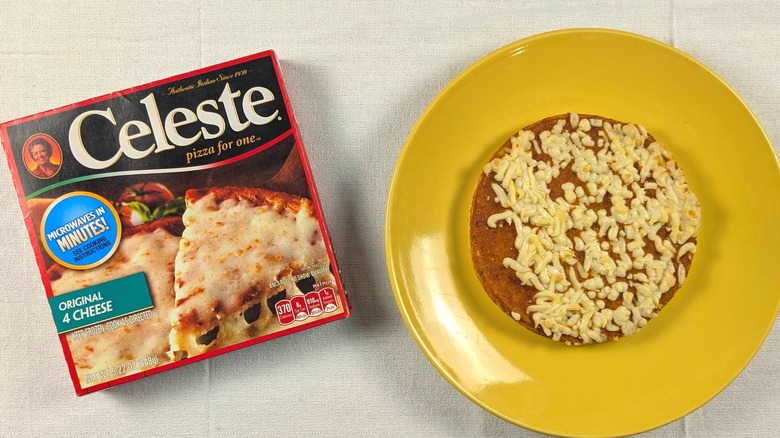 A small, round pizza on a yellow plate next to a Celeste cheese pizza box