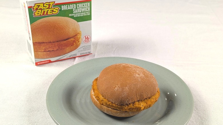 A chicken patty sandwich next to a box for a Fast Bites Breaded Chicken Sandwich
