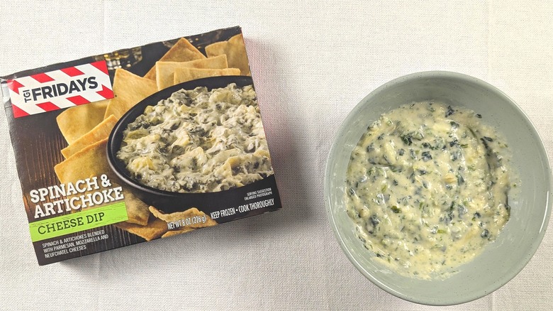 A bowl of spinach artichoke dip next to a box of TGI Fridays spinach artichoke dip