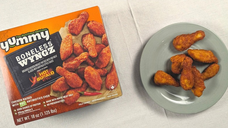A plate of boneless buffalo chicken nuggets next to a box of Yummy Boneless Wyngz