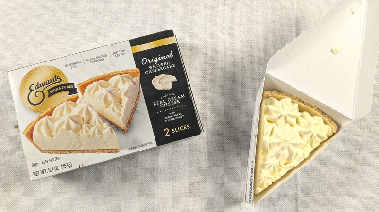 A slice of cheesecake in a triangular box next to a box of Edwards Signature cheesecake slices