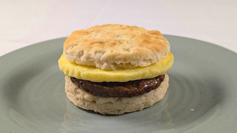 A sausage, egg, and chese biscuit sandwich on a blue plate