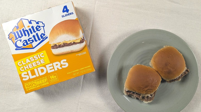 Two sliders on a plate next to a box of White Castle cheese sliders