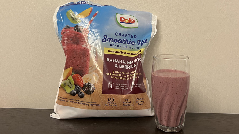 Dole frozen smoothie kit with banana, mango, and berries in glass.