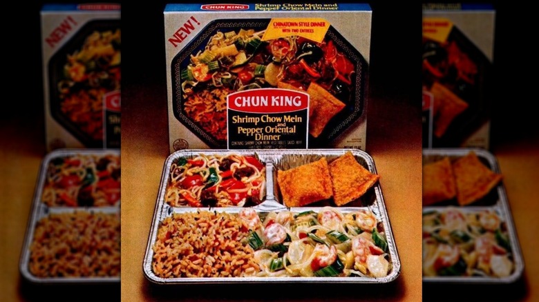An aluminum tray of Chinese food in front of a dinner box
