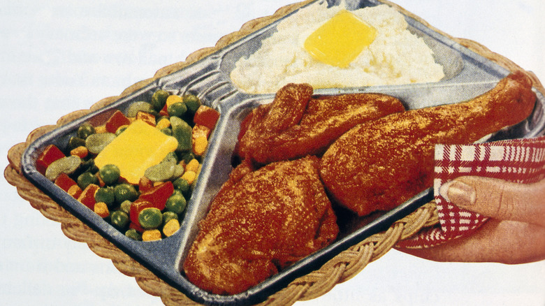 A hand holding a TV dinner tray
