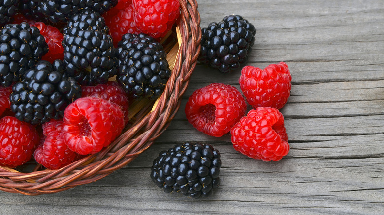Blackberries and raspberries spilling from basket
