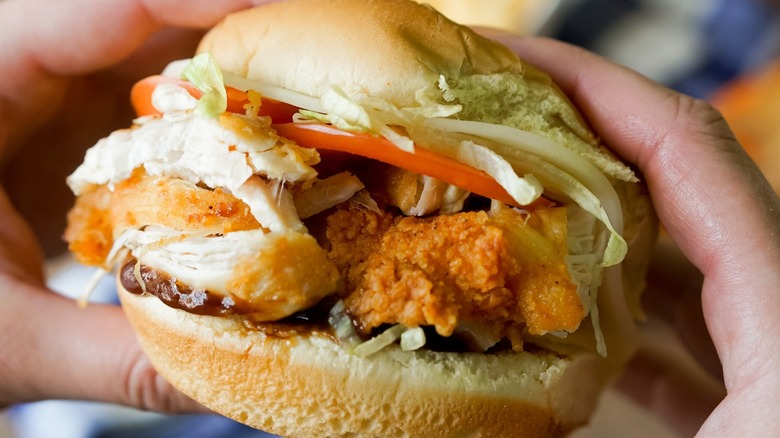 Hands holding chicken sandwich from Royal Farms