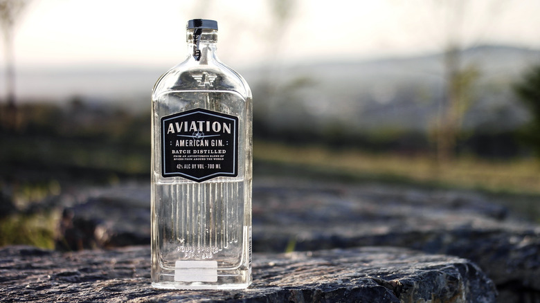 Aviation American Gin showed outside and perched on a rocky setting with a blurred background