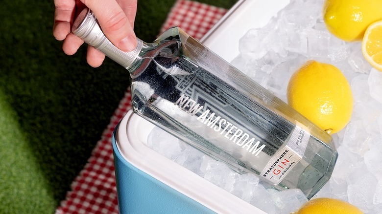 A bottle of New Amsterdam shown being taken out of a cooler with lemons surrounding it