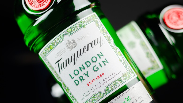 A close up of a bottle of Tanqueray London Dry Gin with another blurred bottle in the background