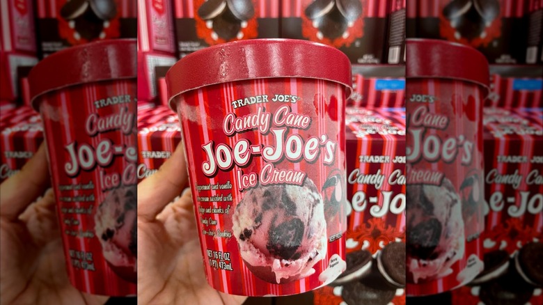 Hand holding Candy Cane Joe-Joe's ice cream in front of boxes of Candy Cane Joe-Joe's