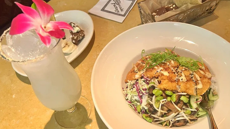 Coconut Limeade Non-Alcoholic Soda with orchid garnish next to chicken katsu bowl