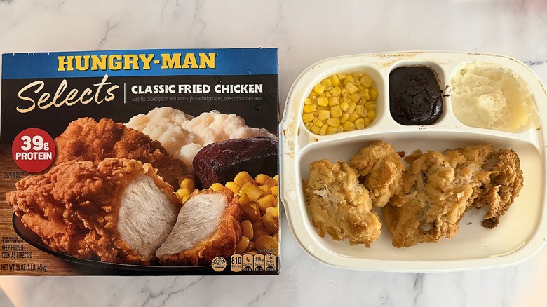 Hungry-Man Classic Fried Chicken box next to cooked meal on marble surface