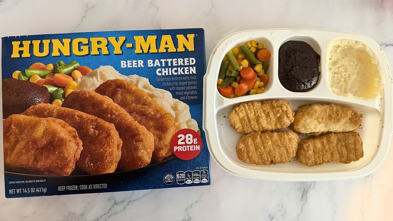 Hungry-Man Beer Battered Chicken box next to cooked meal on marble surface