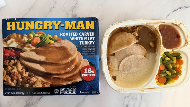 Hungry-Man Roasted Carved White Meat Turkey box next to cooked meal on marble surface