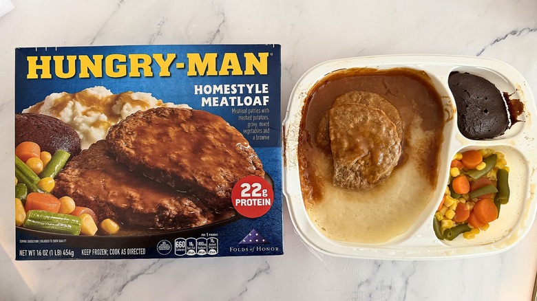 Hungry-Man Homestyle Meatloaf box next to cooked meal on marble surface