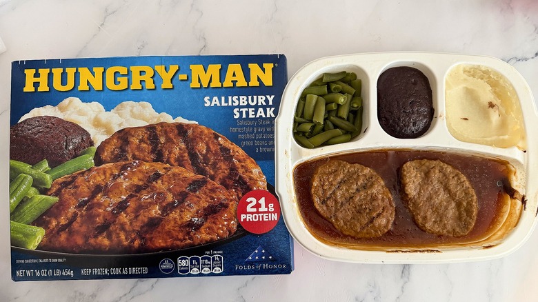 Hungry-Man Salisbury Steak box next to cooked meal on marble surface