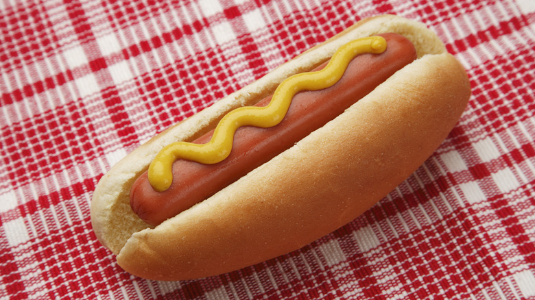 Classic hot dog with mustard on red checkered paper