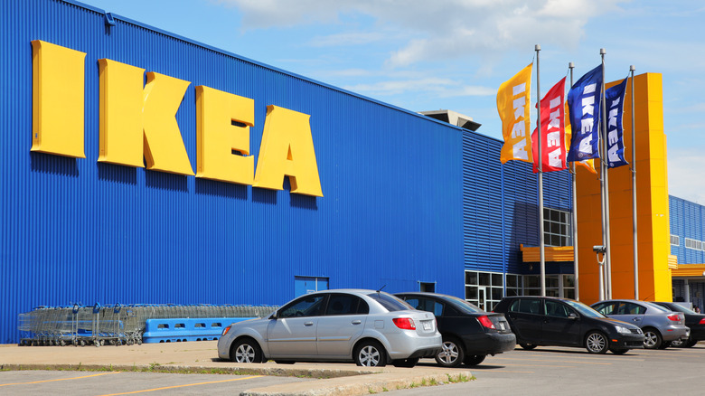 An outside shot of an IKEA store with several vehicles parked outside