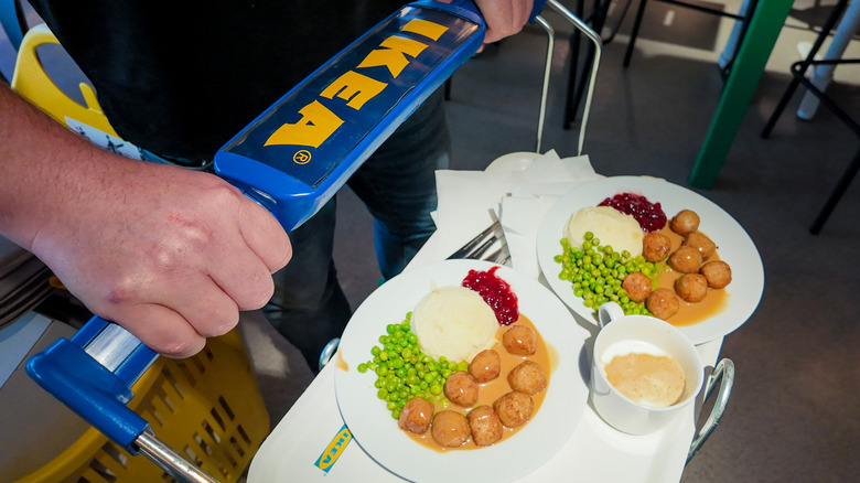 A person holding on to the IKEA carts that are used for carrying multiple trays