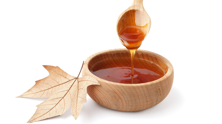 Maple syrup in wooden bowl on white background