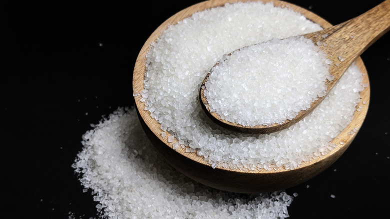 White sugar in wooden bowl with spoon