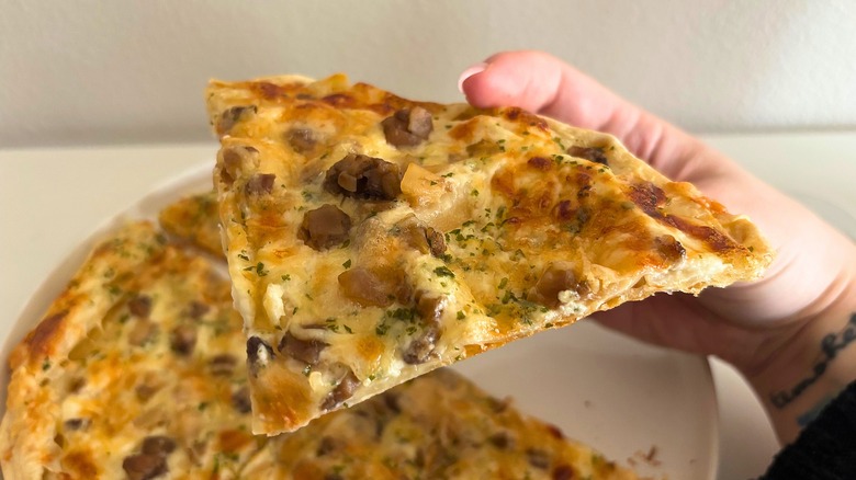 Hand holding a slice of Trader Joe's Tarte aux Champignons