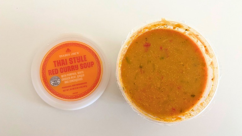 Trader Joe's Thai Style Red Curry Soup in a container next to the lid on a white table