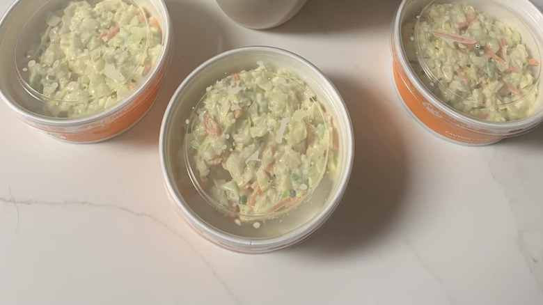 Three containers of Popeyes coleslaw on white table