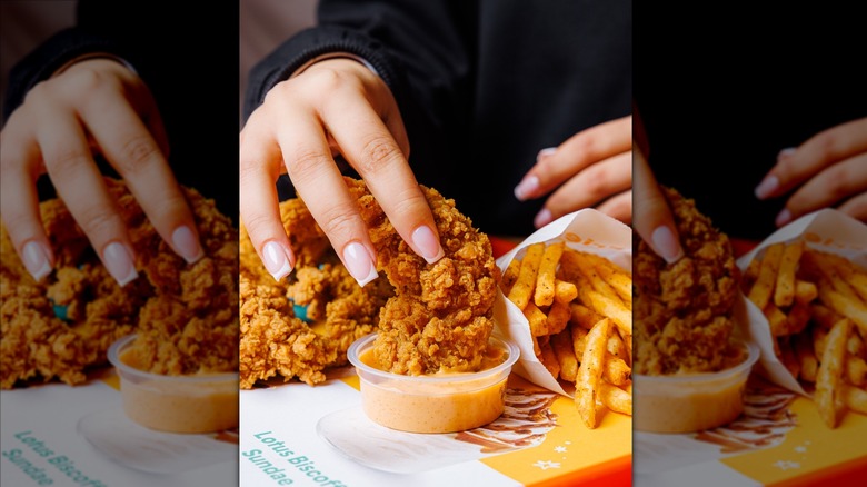 Hand dipping Popeyes spicy chicken tender into sauce