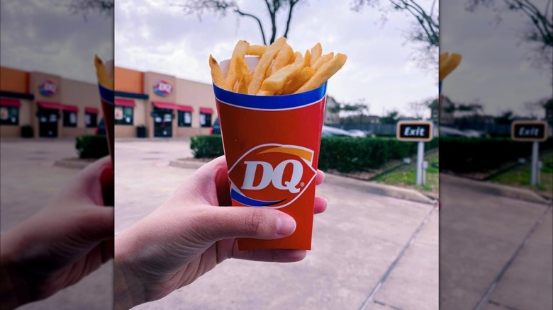 Person holding Dairy Queen fries in front of DQ shop