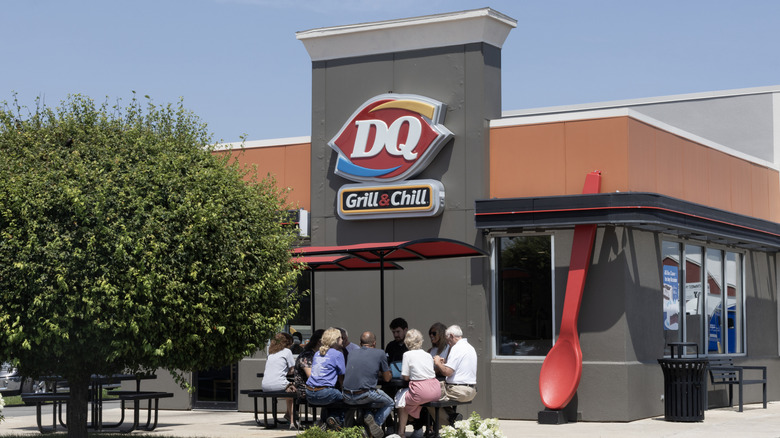 Dairy Queen restaurant exterior sign with a group of people sitting in front