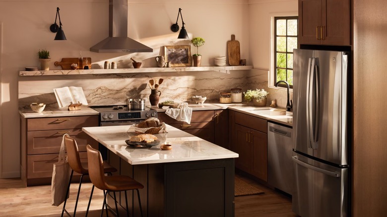 Kitchen with beige and brown color scheme, central island, white marble counters, and steel fridge
