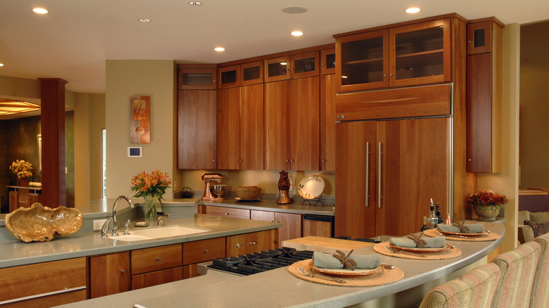 Kitchen with orange wood cabinets and pantry, pale green counters, and dining table