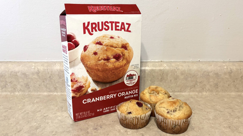 Krusteaz cranberry orange muffin mix box with muffins on neutral counter