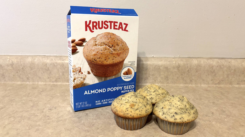 Krusteaz almond poppy seed muffin mix box with muffins on neutral counter