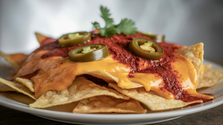 Nachos with cheese and jalapenos on white plate