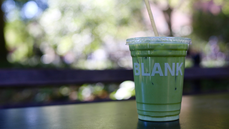 Blank Street Coffee iced matcha latte on table with a straw served in a plastic cup