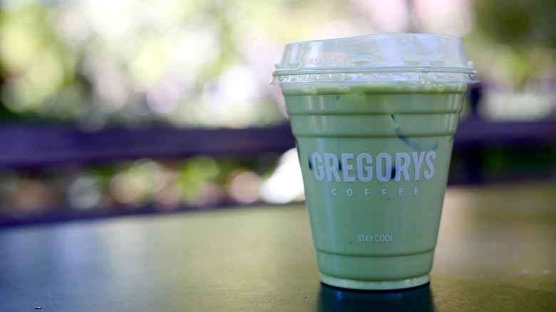 Gregorys coffee iced matcha latte on table served in a plastic cup
