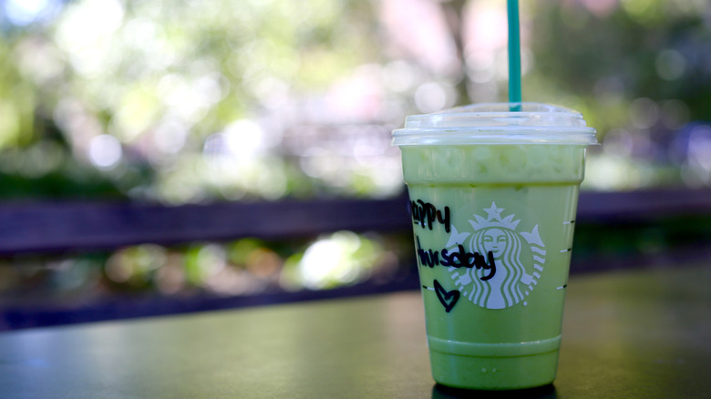Starbucks iced matcha latte on table served in a plastic cup with a straw