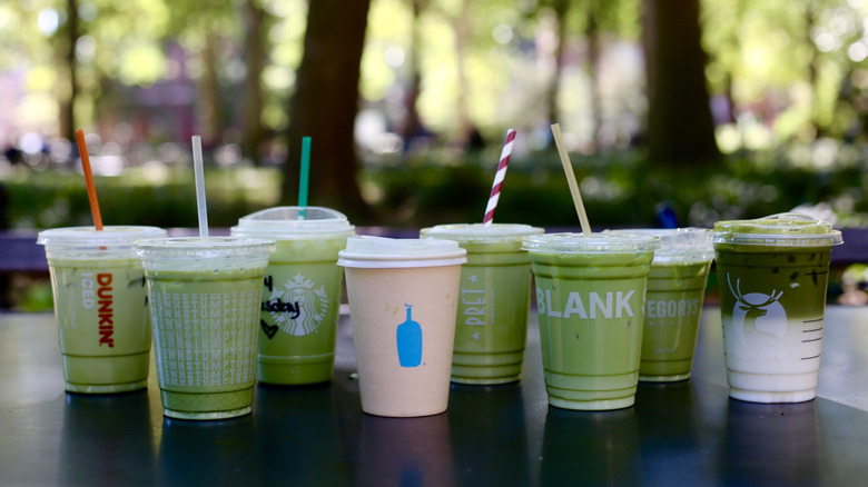 Iced matcha lattes in cups displayed on table
