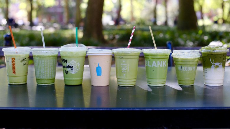 Line of iced matcha lattes assembled on table