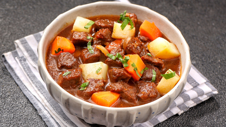 Beef stew served in a bowl on a striped dish cloth