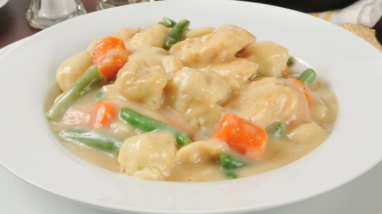 A white bowl of chicken and dumplings